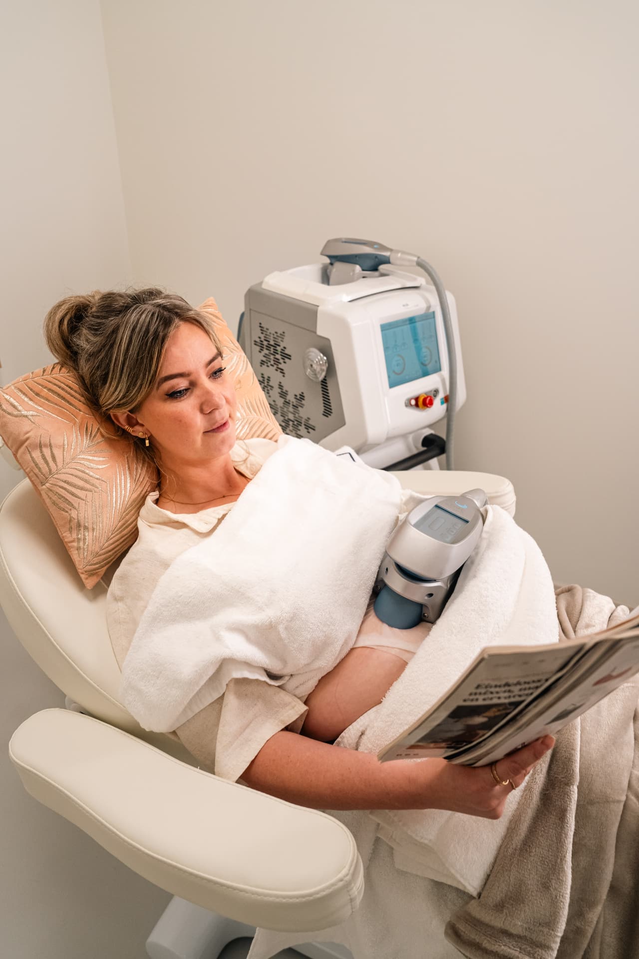 Klant leest ontspannen een tijdschrift tijdens haar cryolipolyse behandeling